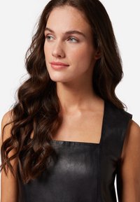 Robe en cuir noir avec un décolleté carré et de larges bretelles. Texture lisse et design ajusté, mettant en valeur un matériau doux et souple.