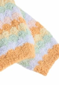 Couverture texturée multicolore avec un fil doux et duveteux dans des teintes pastel de vert, lavande, pêche et orange, ornée d'un motif festonné.