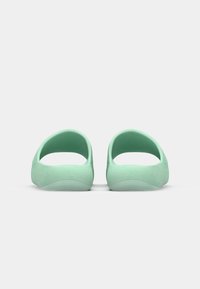 Green slip-on shoes with a rounded open back, smooth texture, and curved soles, designed for comfort and casual wear.