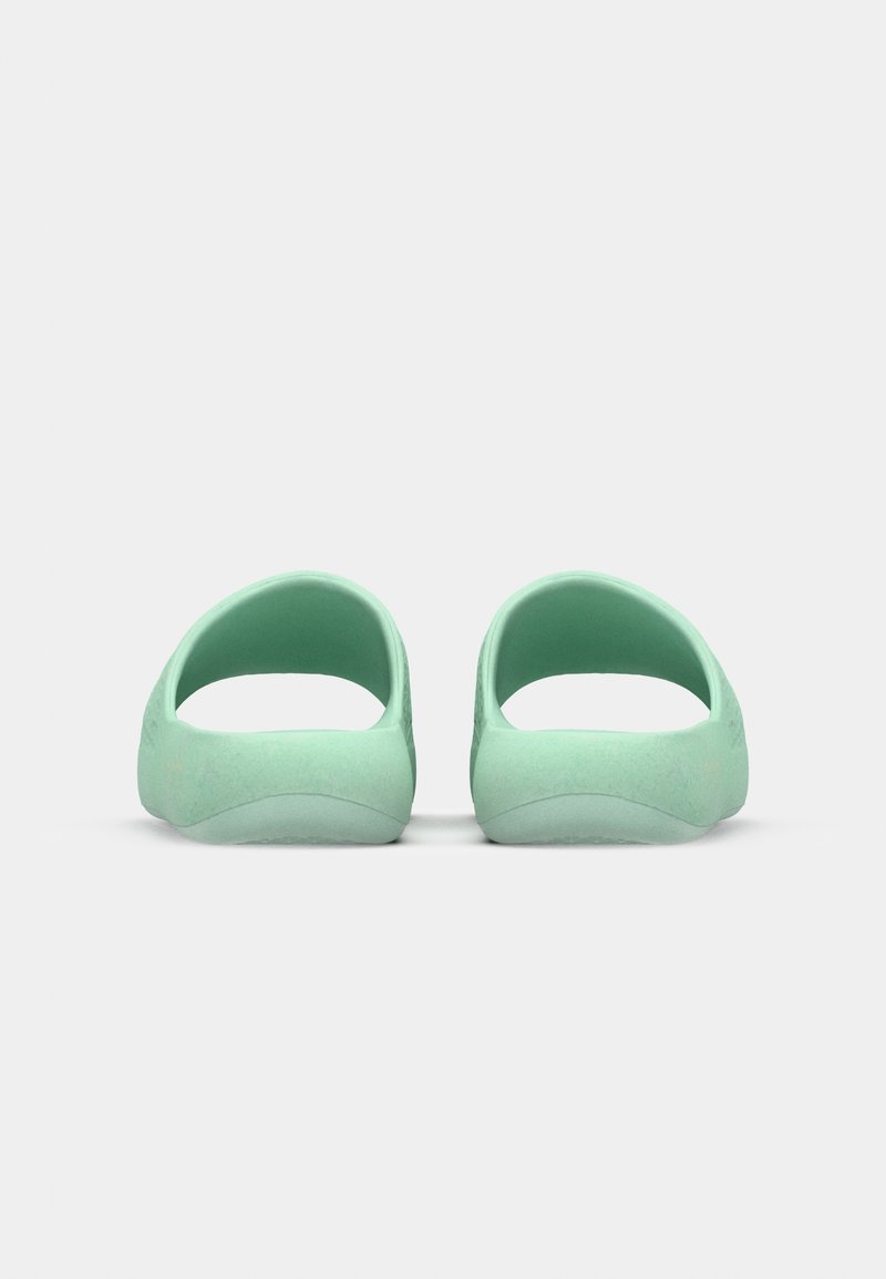 Scarpe slip-on verdi con retro aperto e arrotondato, texture liscia e suole curve, progettate per il comfort e l'uso informale.