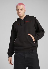 Hoodie noir en mélange de coton, avec une poche kangourou, logo rouge de Formule 1 et accents blancs contrastants sur les poches.