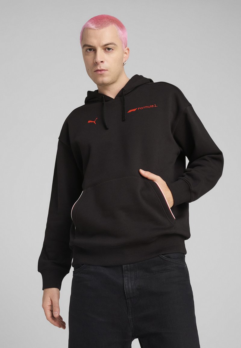 Hoodie noir en mélange de coton, avec une poche kangourou, logo rouge de Formule 1 et accents blancs contrastants sur les poches.