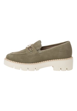 Mocassin en daim vert olive avec semelle blanche épaisse, détail en métal doré sur la tige et bordure cousue le long du pourtour de la semelle.