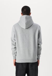 Grå hoodie med en stor, spids hætte, ribbede manchetter og kant, samt et blødt, struktureret stof. Bagsiden er ensfarvet uden synlige mønstre.