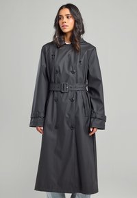 Black waterproof trench coat with double-breasted front, belted waist, hood, and rolled-up sleeves. Smooth texture and knee-length design.