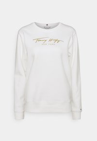 Felpa bianca con ricamo dorato "Tommy Hilfiger New York." Dotata di polsini e orlo a costine, con scollatura rotonda.