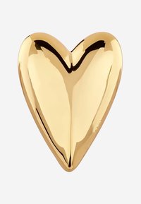 Złoty obiekt w kształcie serca o gładkiej, błyszczącej powierzchni i wyraźnym wgłębieniu w kształcie litery V u góry, odbijający światło. Brak widocznych wzorów lub elementów metalowych.