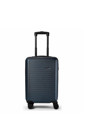 Valise rigide bleu foncé avec des rainures horizontales, poignée rétractable et quatre roues pivotantes, debout sur fond blanc.