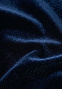 Stofă de catifea bleu marin, cu o textură netedă și lucioasă, prezentând plisuri moi și curgătoare, precum și reflexii ale luminii. Fără modele sau accente vizibile.