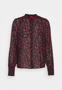 Blouse noire à manches longues avec imprimé floral rouge, boutonnée sur le devant, épaules légèrement froncées et larges poignets.