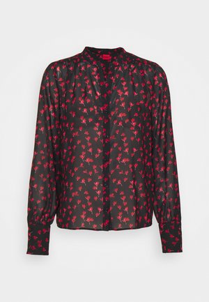 Zwarte blouse met lange mouwen en rode bloemenprint, knoopsluiting aan de voorkant, licht geplooide schouders en brede manchetten.