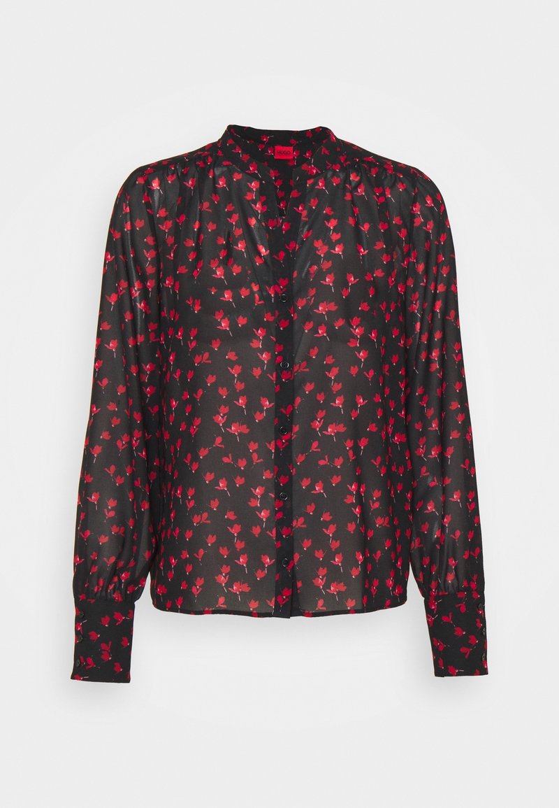 Blouse noire à manches longues avec imprimé floral rouge, boutonnée sur le devant, épaules légèrement froncées et larges poignets.