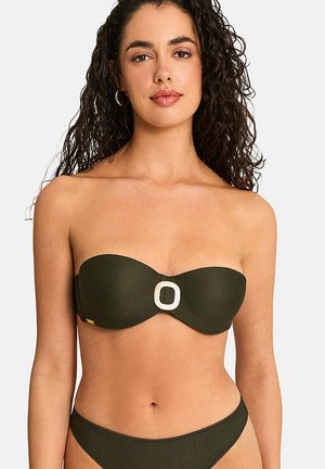 Femme aux cheveux bouclés foncés portant un bikini olive sans bretelles avec un détail boucle blanc au centre devant.
