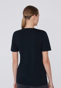 Černé bavlněné tričko s krátkým rukávem, kulatým výstřihem a slim fit střihem. Hladký povrch, žádné viditelné loga ani vzory.