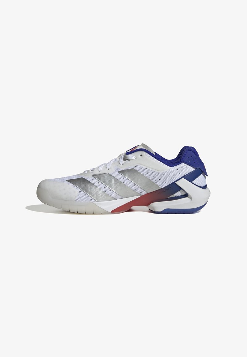 Scarpa sportiva bianca con tomaia in mesh, tre strisce argento, accenti blu e rossi sul tallone, suola texturizzata per presa, design ergonomico moderno.