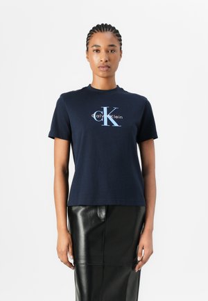 Navy blue cotton t-shirt with short sleeves, round neckline, and large white and light blue Calvin Klein logo printed on the front.