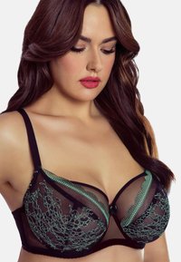 Schwarzer Spitzen-BH mit transparenten Mesh-Cups, die mit grünen bestickten Akzenten und gewellten Kanten verziert sind. Verstellbare Träger und einen Hakenverschluss.