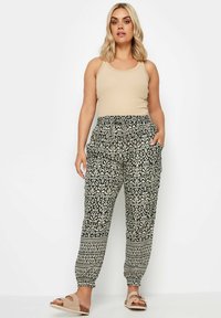 Svarta och vita mönstrade joggare med elastisk midja och sidfickor, tillsammans med en beige linne och lätta skor.