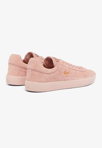 Sneaker rosa realizzati in materiale morbido e testurizzato con bordi lisci e arrotondati. Presentano un profilo basso, punta arrotondata e un'accoppiatura del logo sul lato.