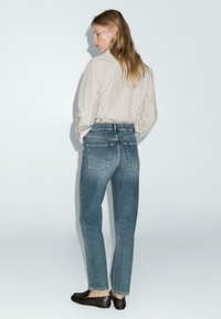 Jeans in denim azzurro chiaro a vita alta con una finitura sbiadita, design a gamba dritta, cinque tasche e dettagli cuciti sul retro.