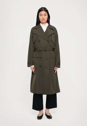 Olive green trench coat with double-breasted buttons, wide collar, belted waist, and front pockets; paired with black wide-leg pants and flats.