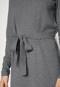 Abito in maglia grigio con maniche lunghe, cintura in vita con nodo e una texture liscia. Silhouette semplice e classica.