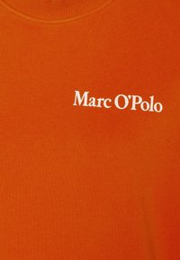 Camiseta de algodón naranja con cuello redondo y un logotipo impreso en blanco "Marc O'Polo" situado en el centro frontal.