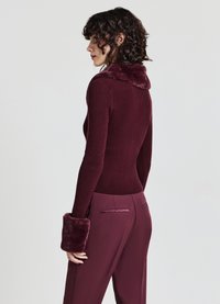 Bordeaux-farbenes, tailliertes Sweatshirt mit geripptem Muster, Kunstfellkragen und -manschetten. Kombiniert mit passenden, maßgeschneiderten Hosen mit eleganten Gesäßtaschen.