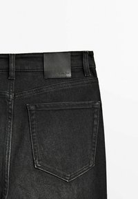 Svarta denimjeans med hög midja, rak passform och bakficka. Inkluderar en liten läderetikett på midjebandet.
