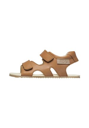 Sandale en cuir marron avec deux brides réglables et un design ajouré, semelle plate blanche et étiquette de marque sur le côté.