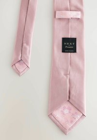 Cravate en satin rose à extérieure unie, avec un motif floral à l'intérieur. Etiquette : "NEXT Occasion," fabriquée en Chine.
