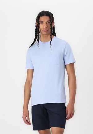 Tricou din bumbac de un albastru deschis, cu guler rotund, mâneci scurte și un detaliu de buzunar pe piept. Purtați-l cu șorturi de un albastru marin închis.