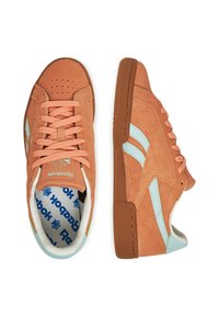 Barna velúr sportcipők világoskék részletekkel, kerek orral és perforált mintázattal. Narancssárga fűzőkkel és logóval a nyelvén. Texturált gumi talp.