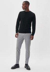 Melnas garām piedurknēm kaklasaišu krekls kopā ar gaiši pelēkiem slim-fit biksēm un melniem mokasīniem, ar gludu tekstūru un minimālistisku dizainu.