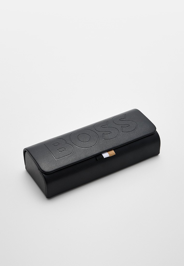 Czarna skórzana etui na okulary z wytłoczonym logo "BOSS", elegancka prostokątna forma oraz minimalistyczny design z małym kontrastowym suwakiem.
