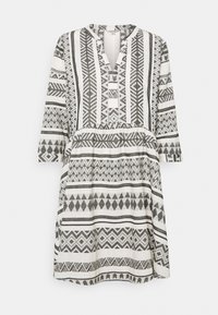 Vestido de patrón en blanco y negro con escote en V, mangas tres cuartos y cintura fruncida. Presenta diseños geométricos y rayas horizontales.