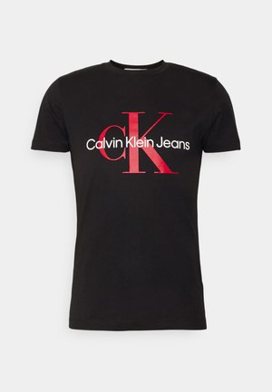 T-shirt en coton noir avec un grand logo rouge "CK" et le texte blanc "Calvin Klein Jeans" en dessous. Manches courtes, design col rond.