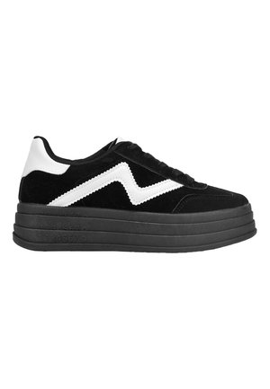 Zapatillas de ante negro con una gruesa suela de plataforma negra, que presentan un diseño de zigzag blanco y acentos en blanco en el talón y la lengüeta.