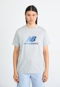 Gray cotton t-shirt featuring a blue "NB" logo and "new balance" text, short sleeves, and a crew neck design.