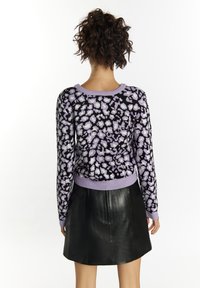 Pulover tricotat cu un imprimeu leopard violet și negru, având un guler rotund și tiv striat. Asortat cu o fustă din piele neagră.