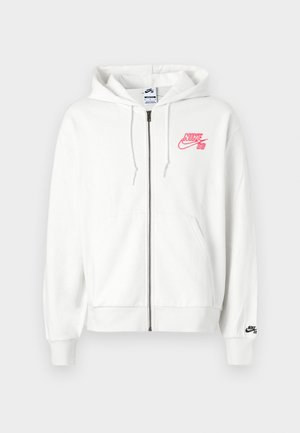 Sudadera blanca con cremallera, hecha de tela suave, con un logo bordado en rosa "Nike SB" en el pecho y un logo negro en el puño izquierdo.