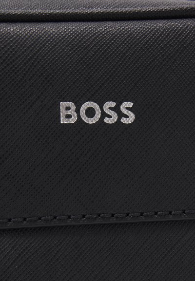 Черна текстурирана материя с релефно лого "BOSS" в сребрист цвят. Разполага с чисти линии и дискретни детайли от шев.
