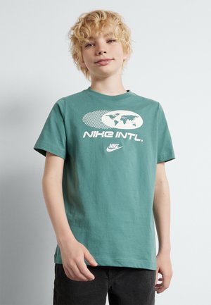 Camiseta de algodón verde con un gráfico blanco que presenta un mapa del mundo y el texto "NIKE INTL.". Con mangas cortas y diseño clásico de cuello redondo.