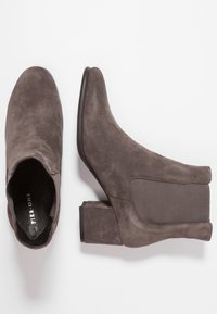 Bottines en suède gris avec un talon carré, des panneaux latéraux élastiques et une texture lisse. Le design présente un bout rond et des détails minimes.