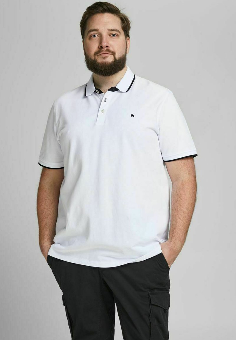 Valkoinen polo-paita mustilla yksityiskohdilla ja kauluksessa. Lyhyet hihat, klassinen malli. Pehmeä rakenne, jossa on pieni logo rinnassa.