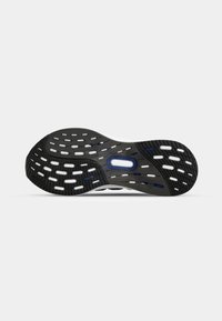 Black rubber shoe sole with cut-out patterns, featuring white accents and a central blue element. Textured for grip, curved shape.