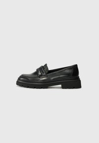 Black leather loafers with a rounded toe, double strap detail, and a thick, textured sole. Features a stitched border for added detail.