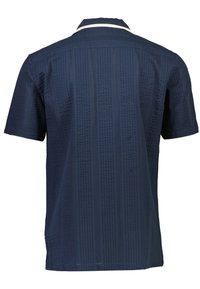 Camisa de manga corta en azul marino oscuro con un patrón texturizado. Presenta un collar plano y una franja blanca en contraste a lo largo del borde del collar.
