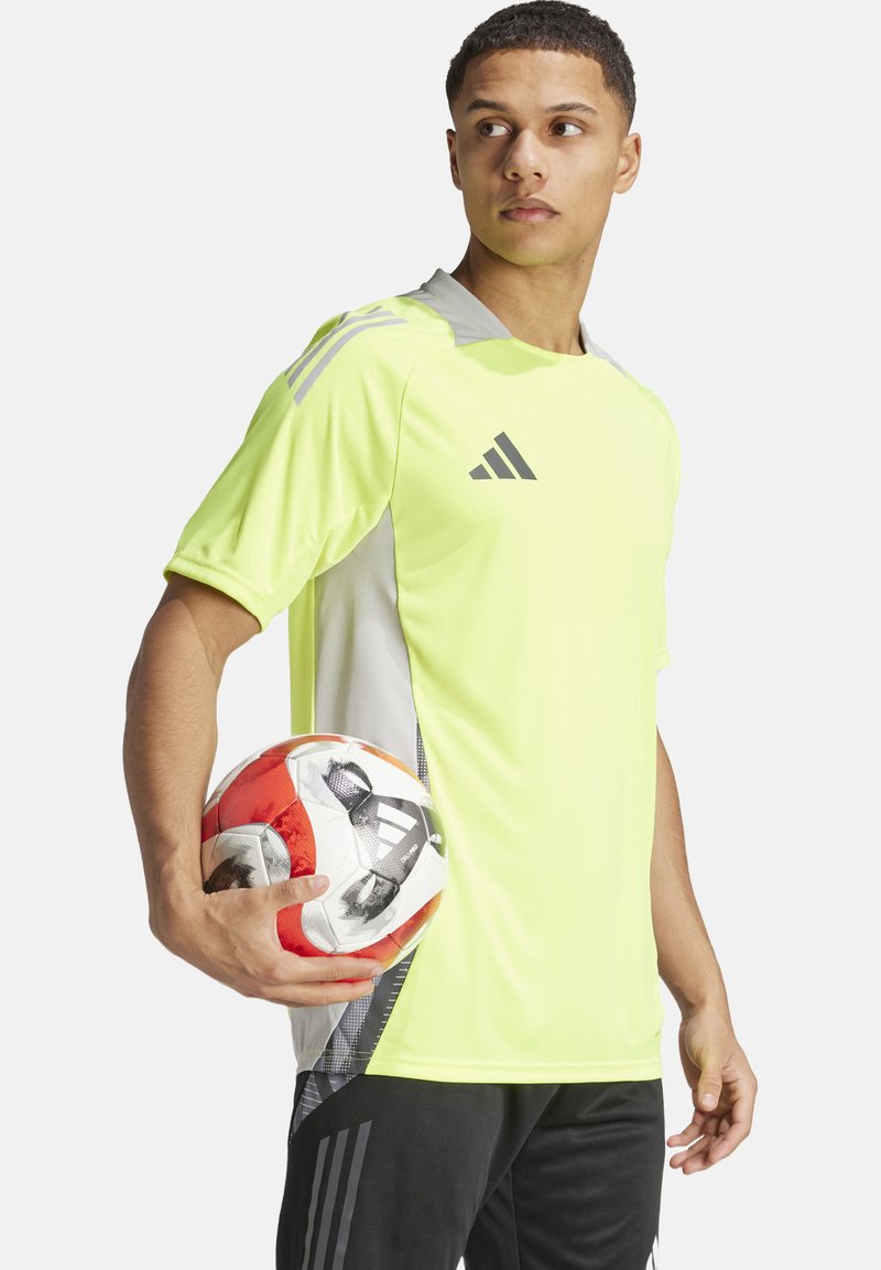Neon-gelbes Adidas-Sportshirt mit grauen Akzenten, kurzen Ärmeln und seitlichen Einsätzen, kombiniert mit einem rot-weißen Fußball.