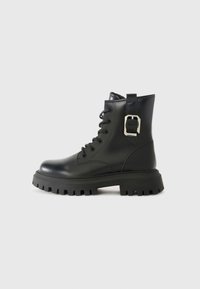 Botas de tobillo de cuero negro con suela gruesa, cordones en la parte delantera y un detalle de hebilla lateral. Textura suave y diseño aerodinámico.